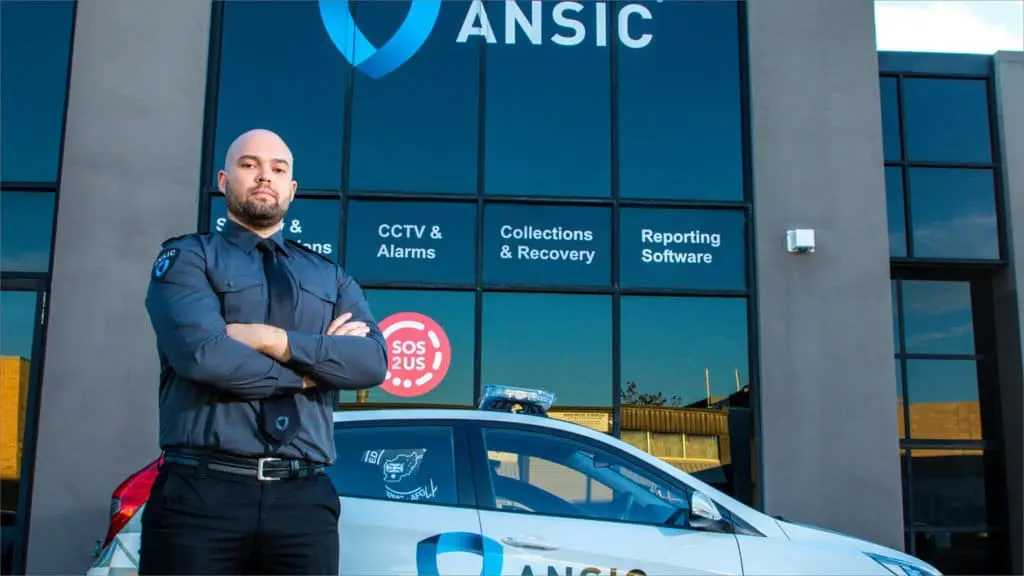 ANSIC security officer beside a marked ANSIC patrol vehicle